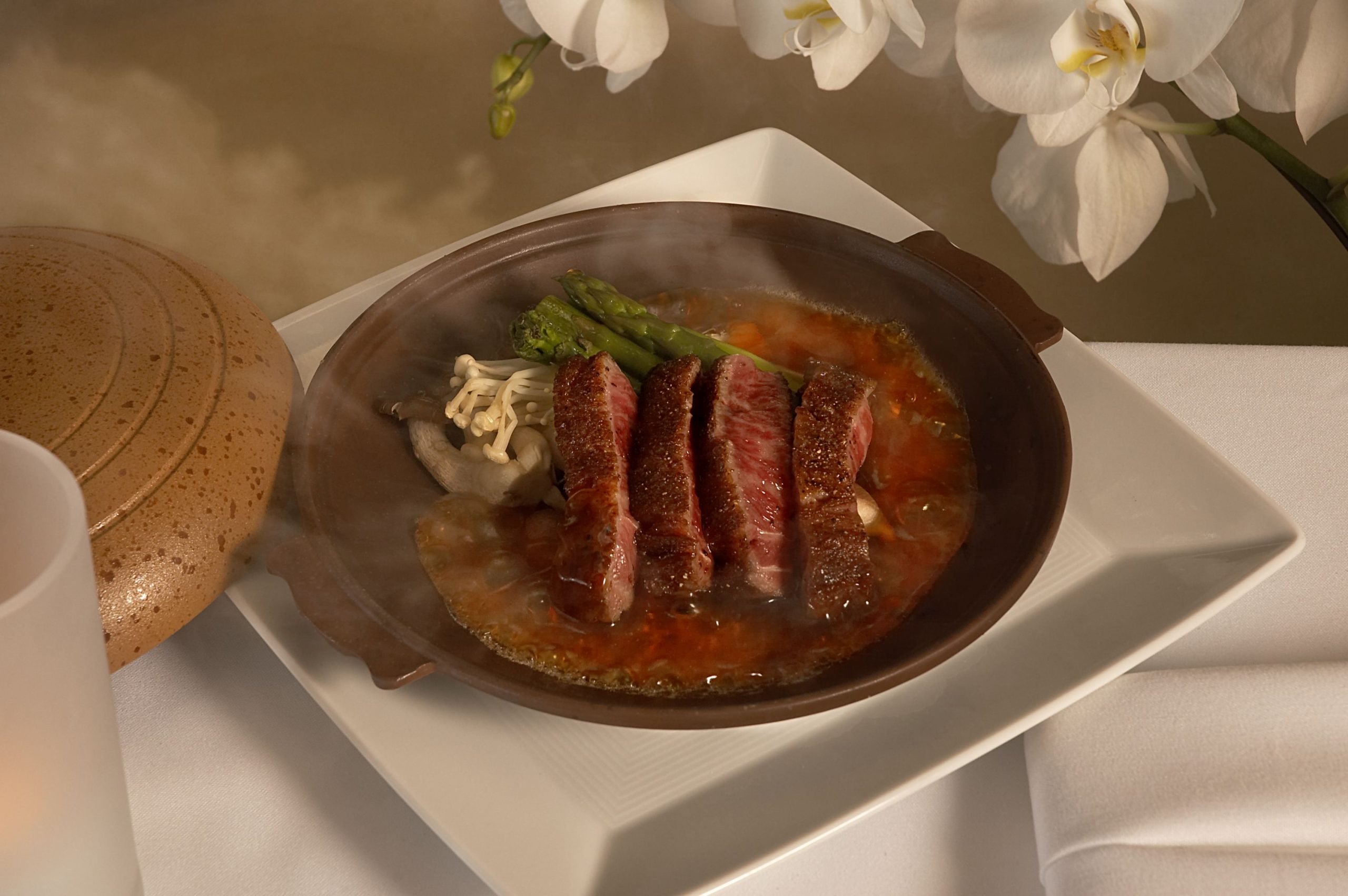 Seared wagyu beef with mushrooms and asparagus in a hot clay pot