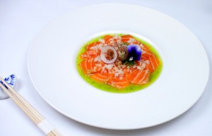 Sliced salmon in basil oil, topped with myoga, onion and an edible flower